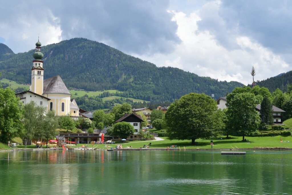 Reithersee uimaranta ja taustalla iso kirkko sekä vihreät Alppivuoret