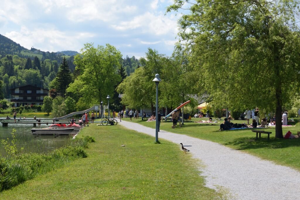 Thiersee uirantan, sorsa kävelee pyörätien yli ja ihmiset ottavat aurinkoa