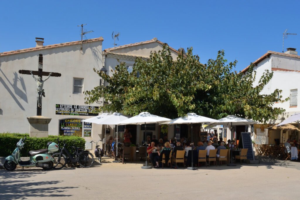 Saintes-Maries-de-la-mer kylän keskusaukio, jossa on ravintola ja sen vierellä on kristillinen risti