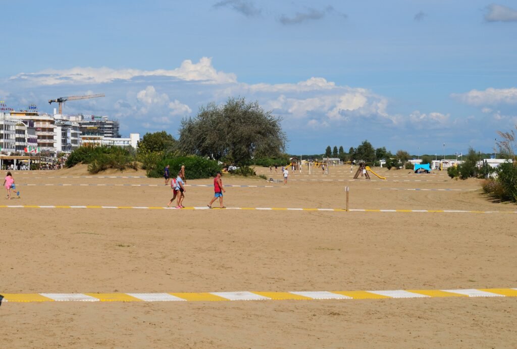 Caorlen leveä hiekkaranta, jossa kävelee ihmisiä